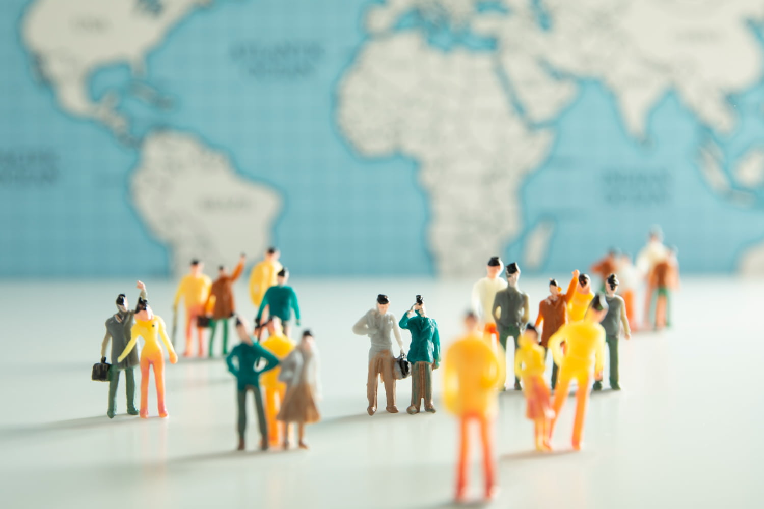 Conjunto de muñecos reunidos simbolizando una sociedad civil con mapa del mundo de fondo.